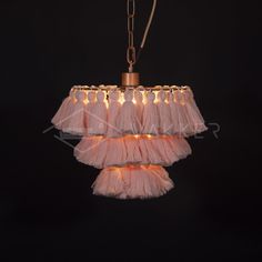 a pink chandelier hanging from a chain on a black background with light bulbs