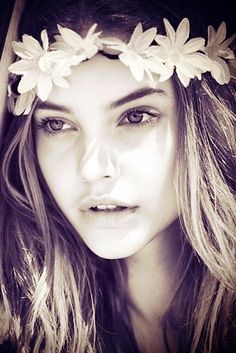 a woman with flowers in her hair wearing a flower headband and looking at the camera