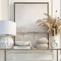 a shelf with vases and other items on it in front of a white fireplace