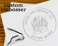 a stamp with the words custom embosser on it next to a pair of scissors