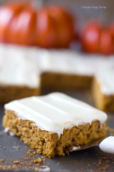 a piece of cake sitting on top of a pan with frosting and pumpkins in the background