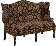 a couch with an ornate pattern on the back and arms, sitting in front of a white wall