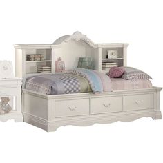 a white bed sitting next to a night stand with drawers on each side and a book shelf above it