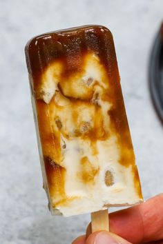 a hand holding an ice lolly with caramel sauce on the top and chocolate in the middle