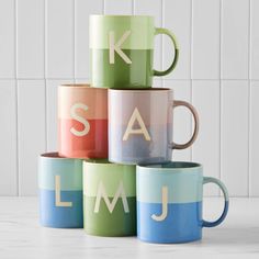 five colorful coffee mugs stacked on top of each other with the letters k, s, and j