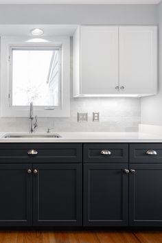 a kitchen with black cabinets and white counter tops