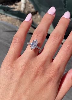 a woman's hand with a diamond ring on her finger and pink nail polish