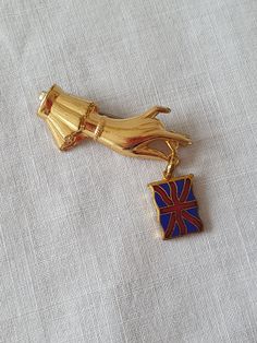 "A comemorative brooch  of a gilt metal hand holding an enamel Union Jack Flag. It fastens with an old style C clasp. On its original card. Condition: In excellent condition. Size:  L: 1 1/2\" (3.5 cm) W: 1\" (2.5 cm) I always package items carefully for shipping. Please feel free to contact me with any questions." Antique Gold Lapel Pin Collectible, Collectible Gold Enamel Pins, Gold Enamel Lapel Pin, Formal Gold Enamel Brooches, Vintage Yellow Gold Enamel Pin Collectible, Vintage Yellow Gold Enamel Pin For Collectors, Victorian Gold Enamel Pin, Antique Gold Enamel Pin For Formal Occasions, Victorian Style Gold Enamel Pin