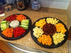 two black plates filled with different types of food on top of a counter next to each other