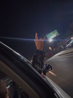 a hand sticking out of the window of a car on a city street at night