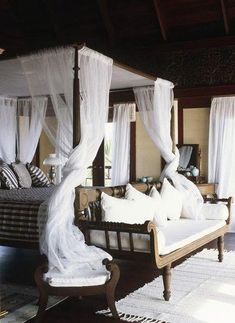 a canopy bed sitting in the middle of a living room next to a white rug