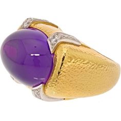 Captivating and alluring, the David Webb Platinum & 18K Yellow Gold Cabochon Amethyst And Diamond Cocktail Ring is a true masterpiece that will captivate your senses. This exquisite ring showcases a large cabochon amethyst, elegantly mounted in an East to West orientation, held securely by a sleek bezel. The deep, vibrant purple hue of the amethyst exudes an air of mystique and sophistication.Adding to its allure, this ring features round cut diamonds delicately placed in the four corners, creat Luxury Yellow Gold Gemstone Cabochon, Luxury Oval Cabochon Gemstones, Luxury Yellow Gold Oval Cabochon Gemstones, Yellow Gold Gemstone Cabochons, Luxury Formal Cabochon Amethyst Ring, Luxury Formal Amethyst Cabochon Ring, Luxury Amethyst Cabochon Ring For Formal Occasions, Luxury Round Cabochon Amethyst Ring, Luxury Domed Cabochons For Formal Occasions