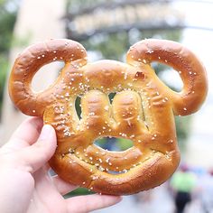 someone holding up a mickey mouse pretzel with sesame seeds on it's face