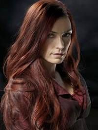 a woman with long red hair standing in front of a dark background and looking at the camera