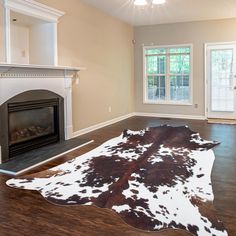 an empty living room with a fireplace and cow hide rug on the floor in front of it