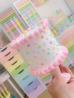 a hand holding a birthday cake with sprinkles