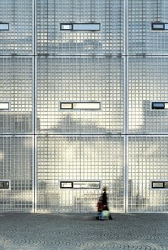 a person sitting on a bench in front of a building with many windows and bars