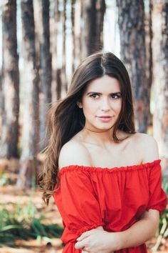 a beautiful young woman posing for a photo in the woods with her hair blowing back