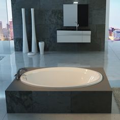 a large white bath tub sitting in a bathroom next to a tall vase and sink