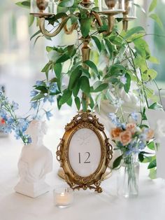 a clock sitting on top of a table next to vases with flowers and candles