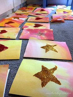 several pieces of paper with gold glitter stars on them sitting on the floor in front of a door