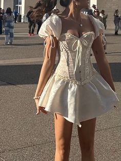 a woman in a white corset is walking down the street with her hand on her hip