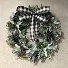 a christmas wreath with pine cones, evergreens and other greenery is hung on the wall