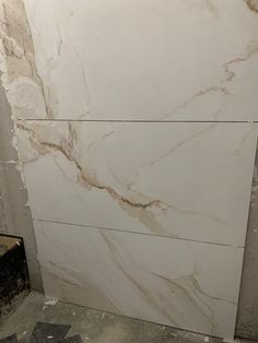 a bathroom with white marble walls and flooring that is being installed on the wall