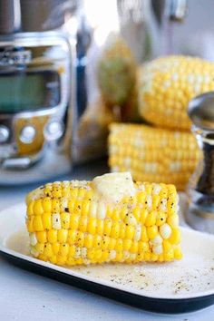 grilled corn on the cob with butter and seasoning next to an instant pressure cooker