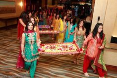 women dressed in colorful outfits are carrying a table with flowers and garlands on it