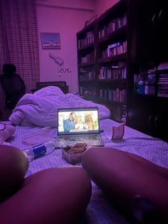 a laptop computer sitting on top of a bed next to a pink light in a bedroom