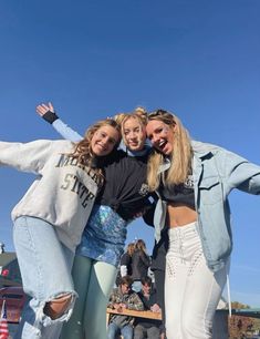 three girls posing for the camera with their arms around each other in front of a crowd