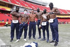 the men are standing on the field with their arms around each other and wearing masks