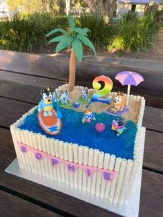 a birthday cake that looks like it is in the shape of a pool with cartoon characters on it