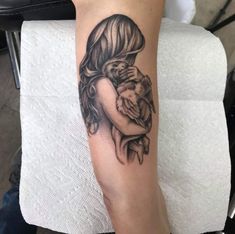 a woman with a tattoo on her arm holding a small child in her arms,