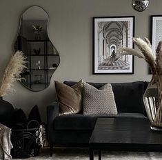 a living room filled with lots of furniture next to a wall mounted mirror and vase