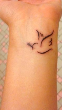 a small tattoo on the wrist of a woman with a bird flying above her head