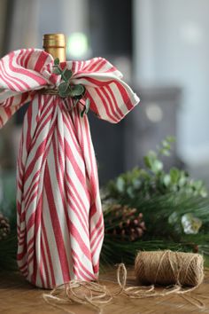 a bottle wrapped in red and white candy canes next to twined twine