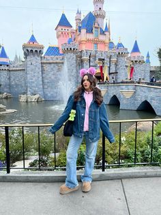 a woman standing in front of a castle wearing a pink hat and blue denim jacket