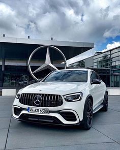 a white mercedes suv parked in front of a building