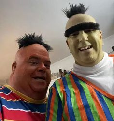 two men dressed up in costumes posing for a photo with one man's hair sticking out