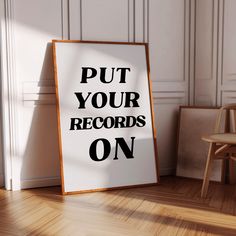 a sign that says put your records on in front of a wooden chair and wall