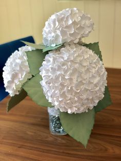 a vase filled with white flowers on top of a wooden table