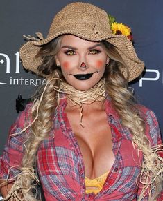 a woman wearing a straw hat and dress with fake eyelashes on her face is posing for the camera