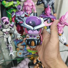 a hand holding a toy in front of a bunch of action figures