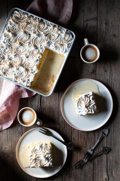 a piece of cake sitting on top of a white plate next to two cups and saucers