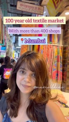 a woman standing in front of a store with an ad on the wall behind her