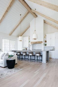 a large open concept kitchen and living room with wood floors, white walls and beams