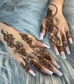 two hands with henna tattoos on them, one is white and the other is brown