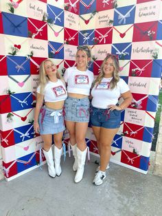 three women standing next to each other in front of a red, white and blue wall